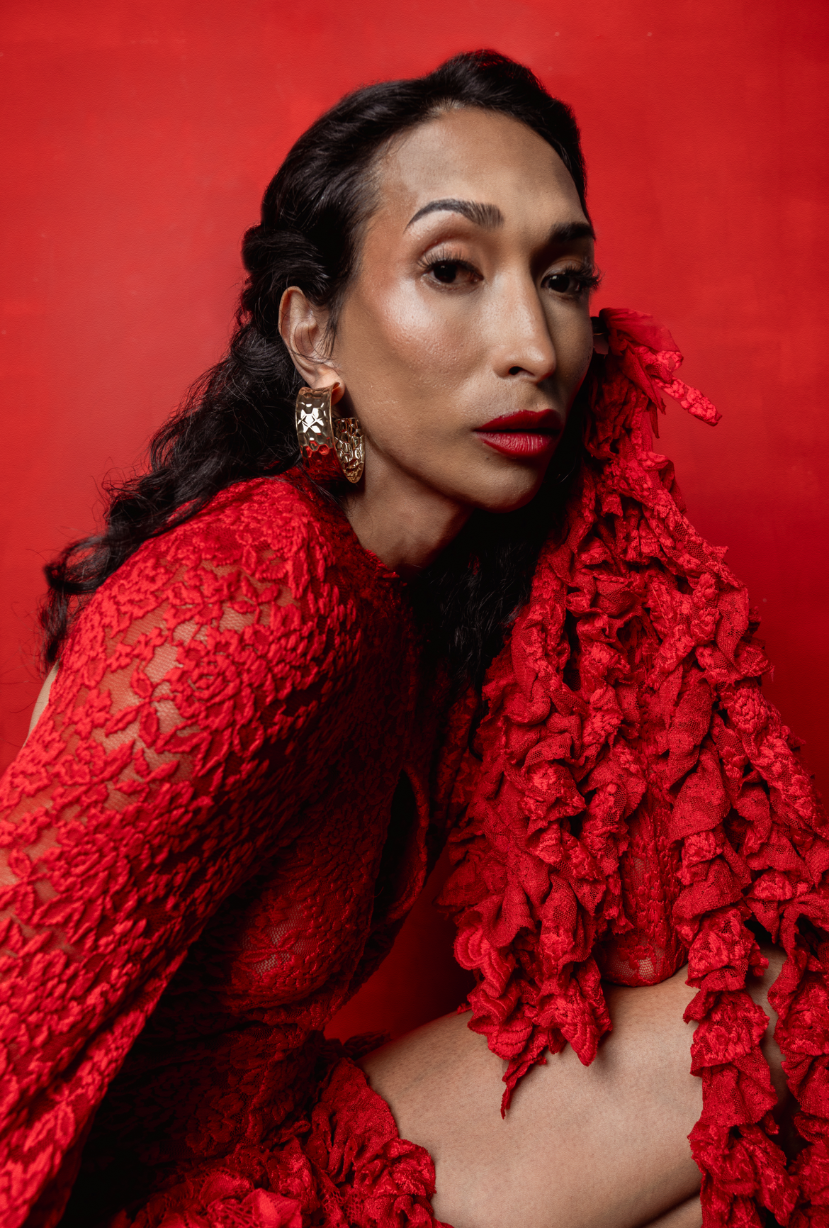 Person wearing a red lace garment against a red background