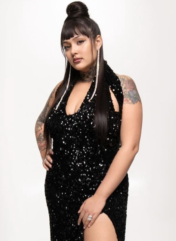 Woman wearing a black sequin dress with a high slit on a white background